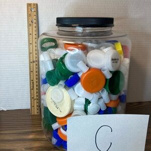 Multicoloured recycled, bottle, caps in two gallon plastic jar